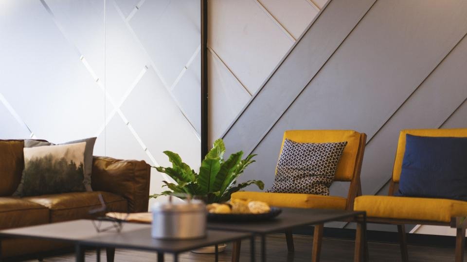 Salon avec un mur habillé de panneaux décoratifs à motif géométrique derrière un canapé et des fauteuils